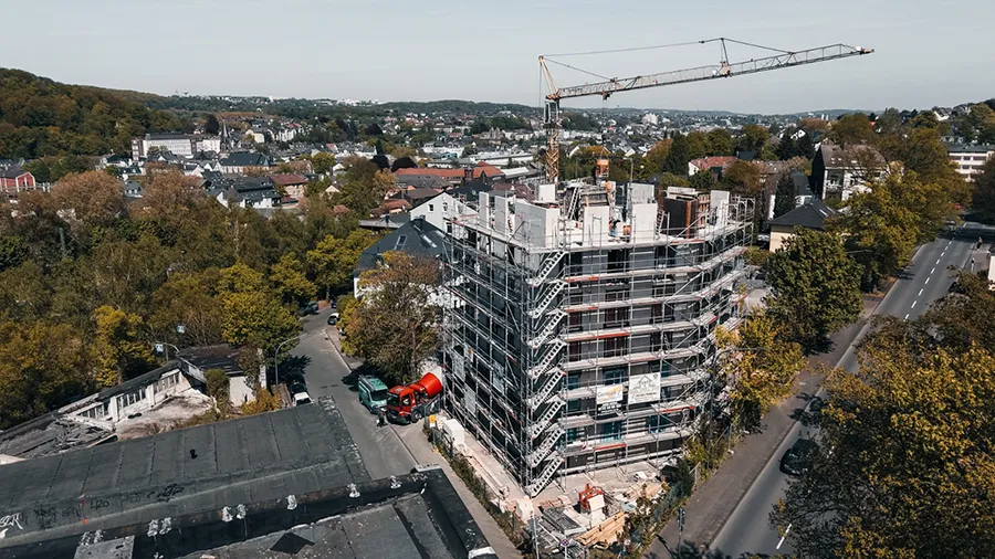 Baustelle am Christbusch mit Baukran, Gerüst und Wohngebäuden im grünen Stadtviertel.