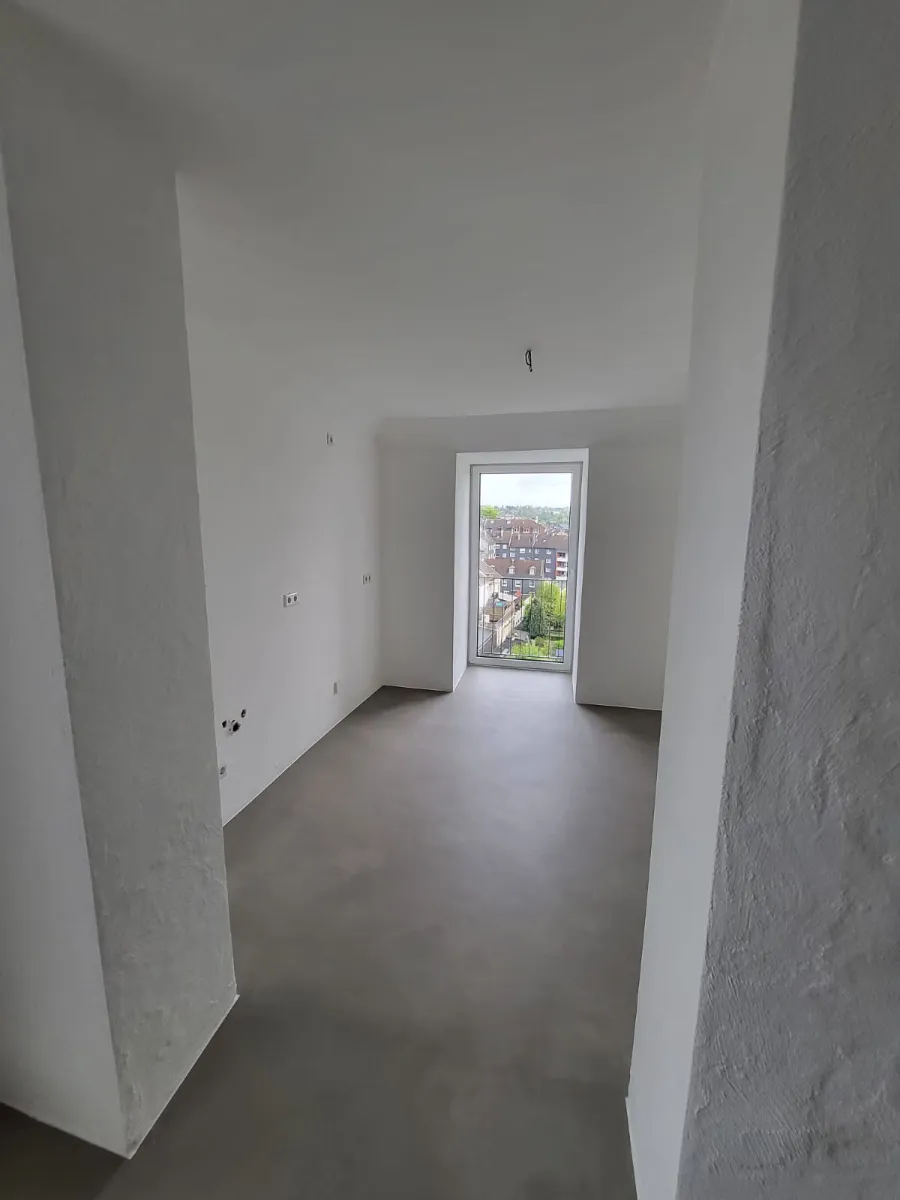 Moderner Bunker-Innenraum mit Betonboden, weißen Wänden und Tageslicht.