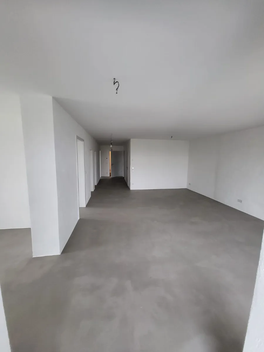 Moderner Bunker Innenraum mit Betonboden, weißen Wänden und offenem Grundriss.