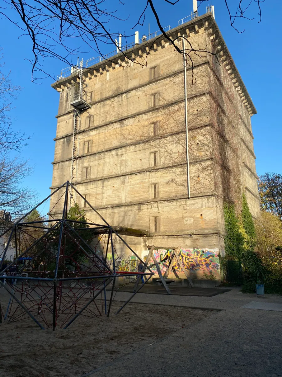 Massiver Betonbunker in der Sonne mit Graffiti und Spielplatz.