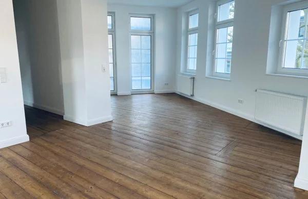 Helle Wohnung mit Holzboden, großen Fenstern und weißem Interieur.