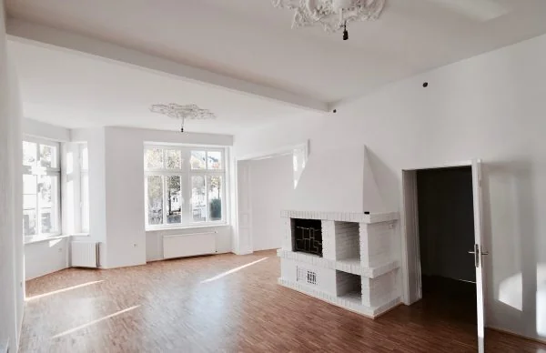 Denkmalgerechte Sanierung eines Wohnhauses: heller Wohnraum mit Holzboden und Kamin.