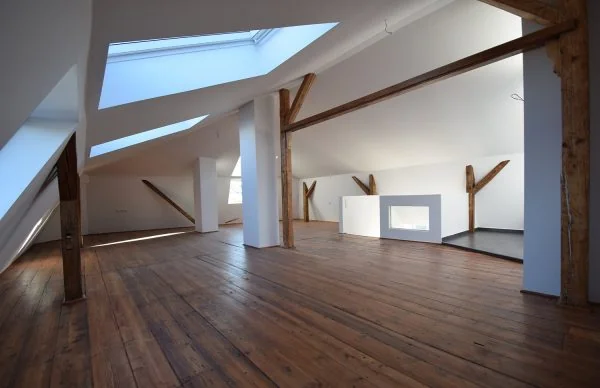 Denkmalgerechte Sanierung eines Dachgeschosses mit Holzboden, Sichtbalken und modernen Dachfenstern.