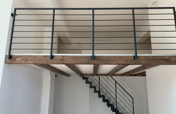 Industrielles Loft mit Galerie, Metalltreppe, Holzträgern und weißem Innenraum.