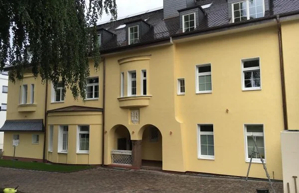 Gelbe Villa im Grünen mit Innenhof, Dachgauben und historischem Charme.