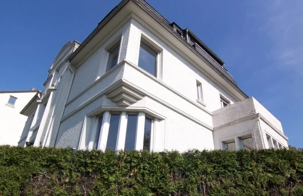 Ehemalige Bürovilla Herberts mit weißer Fassade, Erker und gepflegter Hecke.