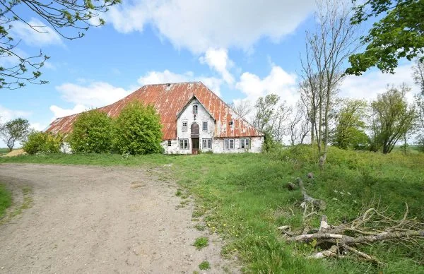 Ferienanlage Katharinenhof mit historischem Bauernhaus, rostigem Dach und grüner Landschaft.