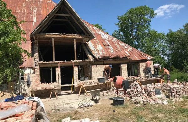 Renovierung alter Scheune in der Ferienanlage Katharinenhof mit Bauarbeitern und Ziegeln.