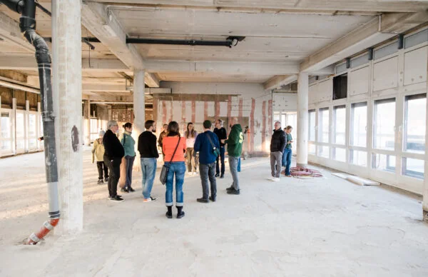 Baustellenbesichtigung im Greenhouse am Neumarkt mit offener Bürofläche und großen Fenstern.