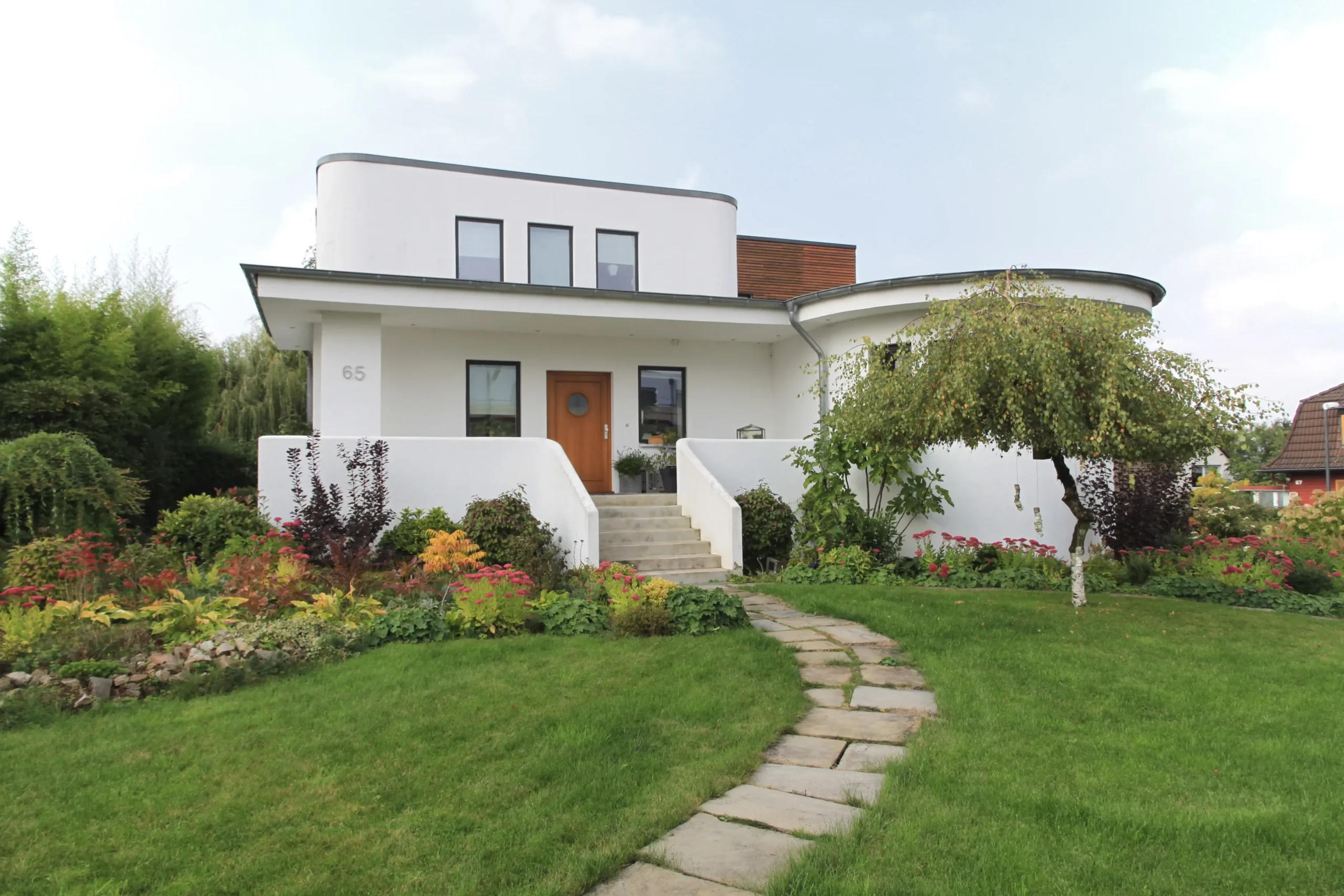 Modernes weißes Einfamilienhaus mit gepflegtem Garten und zeitgemäßer Architektur.