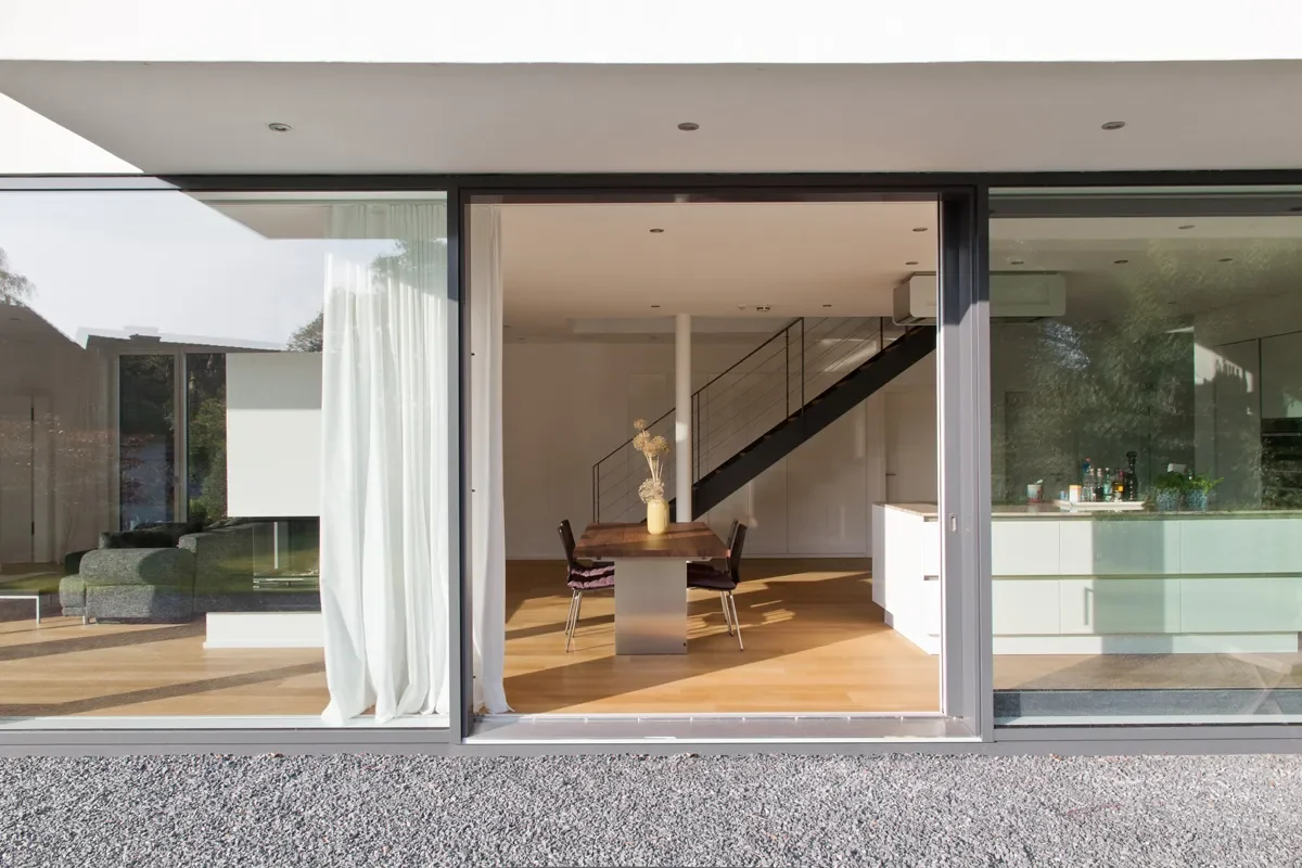Modernes Haus mit Glasfassade, offenem Wohnbereich, Esszimmer und Küche.