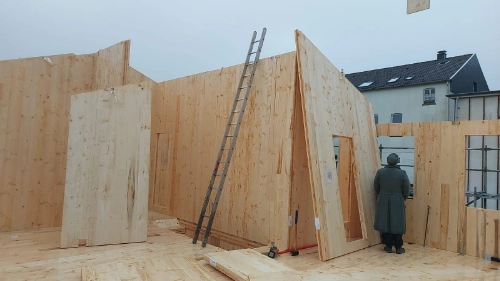 Holzhausbau mit vorgefertigten Holzpaneelen, Innenwänden und Baustelle im Rohbau.