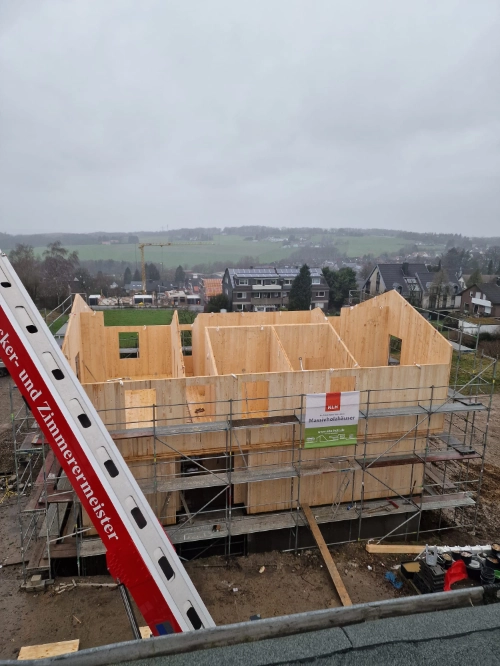 Holzhaus im Bau aus der Luft mit Gerüst auf Baustelle.