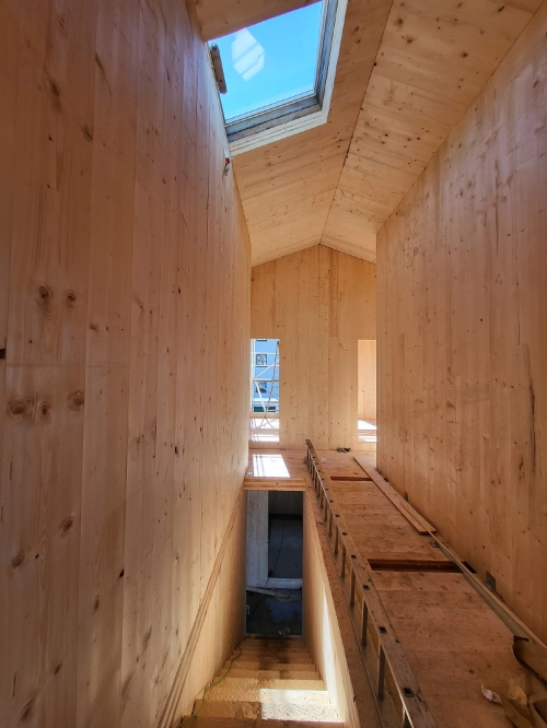 Holzhaus Innenausbau mit Holzverkleidung, Dachfenster und Treppenhaus im Rohbau.