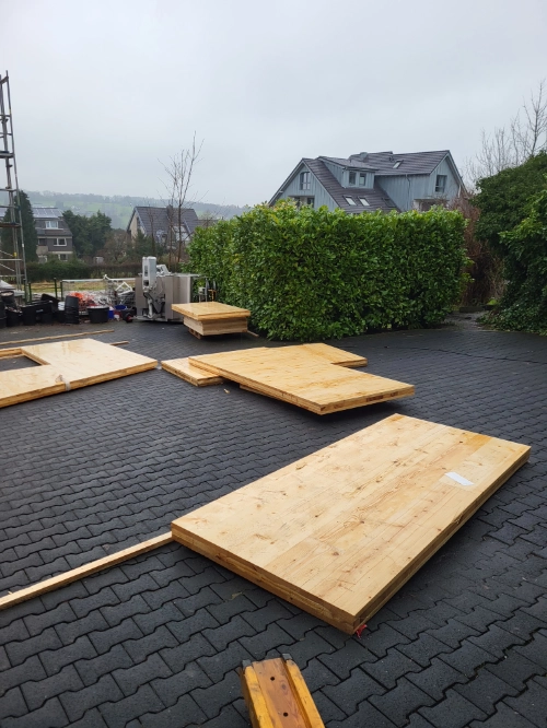 Holzhaus-Materialien: große Holzplatten auf Baustelle im Außenbereich.