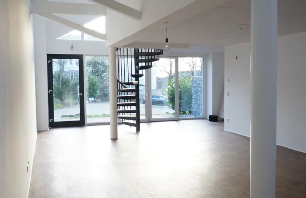 Helles Loft im Backsteinhaus mit Holzfußboden, Glasfront und schwarzer Wendeltreppe.