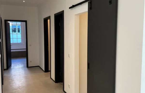 Moderner Loft-Flur mit schwarzer Schiebetür, weißen Wänden und Betonboden in Ronsdorf.