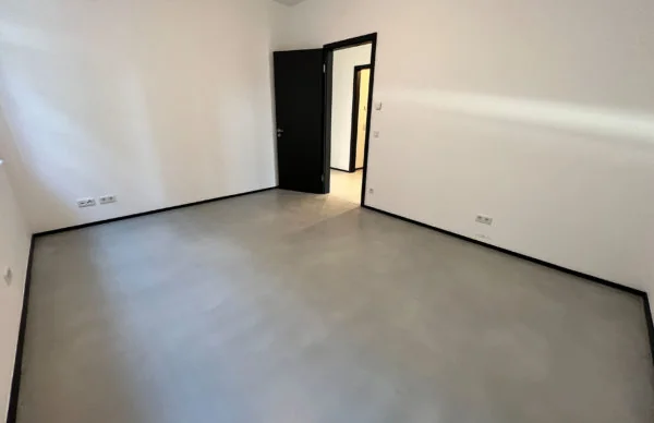 Modernes Loft in Ronsdorf mit grauem Boden, weißen Wänden und schwarzer Tür.