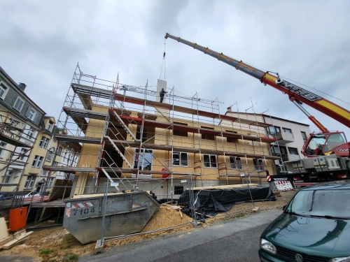 Massivholz-Mehrfamilienhaus im Bau mit Gerüst und Kran.