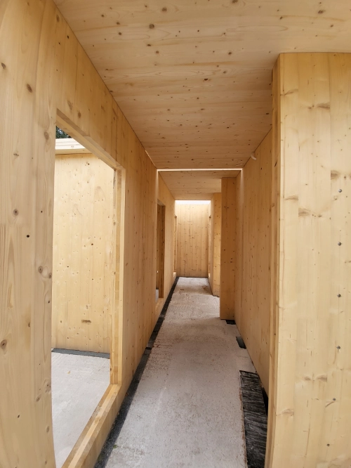 Innenausbau eines Massivholz-Mehrfamilienhauses mit hellem Holzflur im Rohbau.