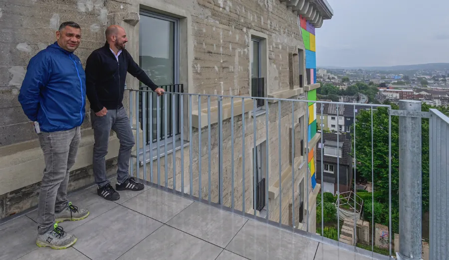 Zwei Männer auf Bunkerterrasse mit Stadtblick und urbaner Architektur.