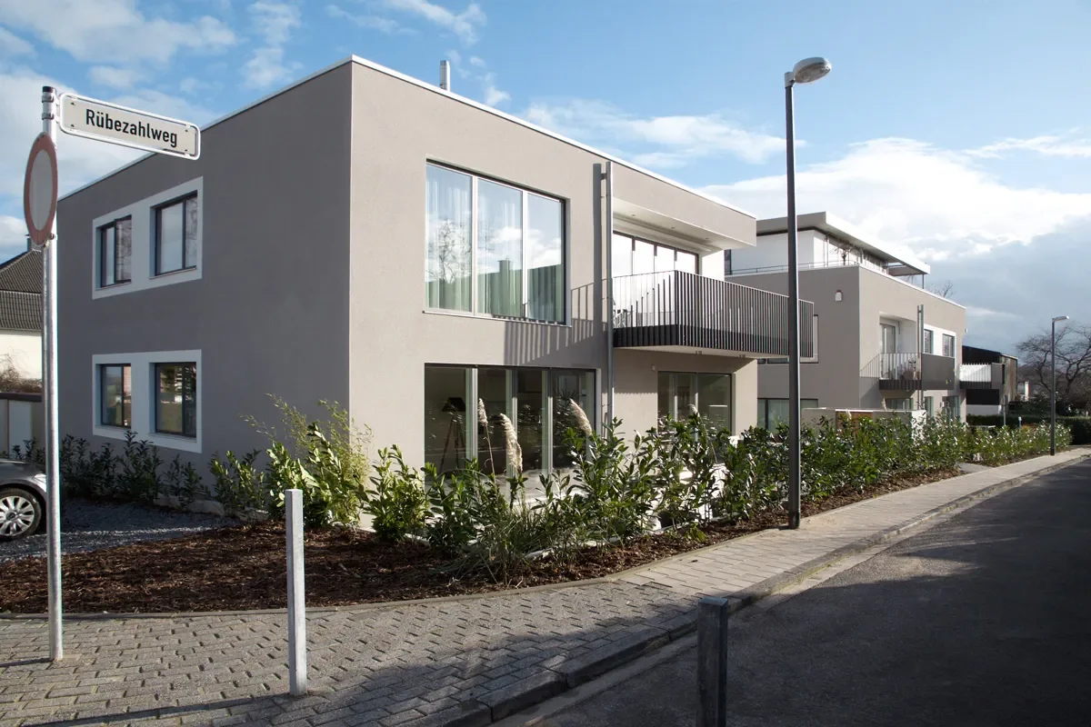 Modernes Mehrfamilienhaus am Rübezahlweg mit Balkonen, Gärten und heller Fassade.