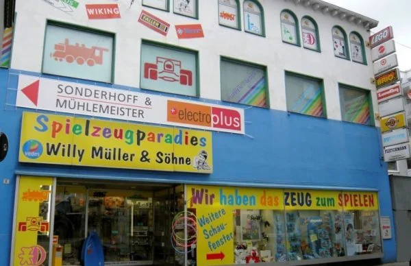 Bunte Spielzeugladen-Fassade am Geschäftshaus Luisenstraße 25 mit Schaufenstern.