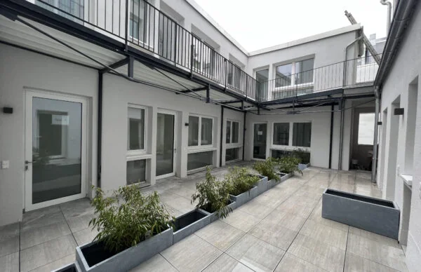 Moderner Innenhof des Geschäftshauses Luisenstraße 25 mit Balkon, Glasfassade und Pflanzkübeln.