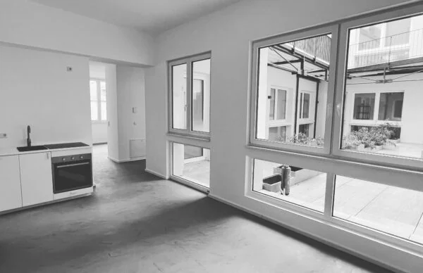 Nutzungsänderung Luisenstraße 25: modernes Apartment mit Küchenzeile und großen Fenstern.