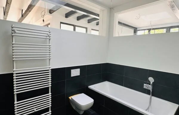 Modernes Schwarz-Weiß-Bad mit Badewanne, wandhängendem WC und Handtuchheizkörper.