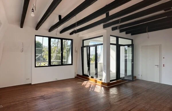 Heller Loft-Raum mit Holzboden, Deckenbalken, Glasfront und Wintergarten.