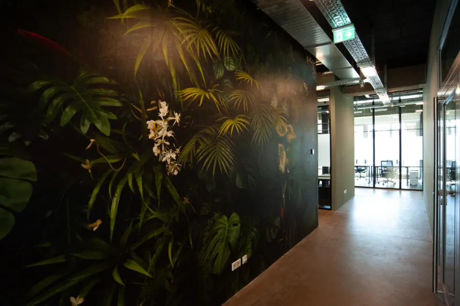 Moderner Büroflur mit dunkler Dschungel-Tapete, Glaswänden und industriellem Design.