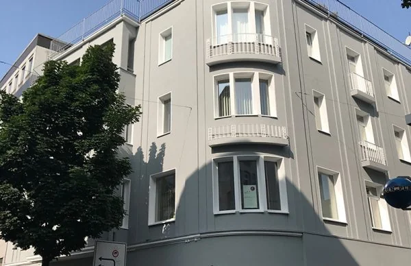 Wohn- und Geschäftshaus in Wuppertal mit grauer Fassade und Erkerfenstern.