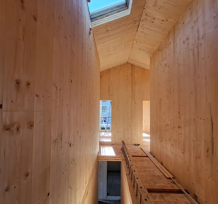 Holzhaus-Innenausbau mit CLT-Platten, Dachschräge und Oberlicht.